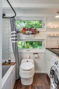 Space-saving pocket doors open to a bathroom complete with gorgeous subway tile, a Jacuzzi tub, a composting toilet, and even a washing machine. #refinery29 http://www.refinery29.com/2016/08/118903/new-frontier-alpha-tiny-home#slide-4