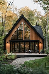 Modern nordic house with veritcal wooden siding black a frame roof large windows small patio shrubs gravel lining in a forest. Indulge in the charm and functionality of Nordic houses, their design principles, key features, and all that makes them so awesome.