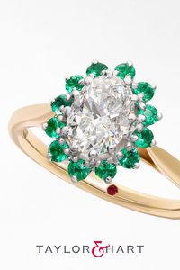 Mixed metal yellow gold and platinum Lyra with an emerald halo engagement ring and oval diamond centre #engagementring #emerald #halo #diamond #floral #oval