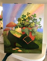 "Here's a fun St. Patrick's Day image, made from an original painting I did. A pot of shamrocks sits next to a velvet green shoe with a golden buckle. The shoe is filled with Irish gold coins ~ did the Leprechauns leave them there for you? The print is 10\"x 8\". It's adhered to illustration board, and hangs from green satin ribbons. Tie the ribbons in a pretty bow, and hang the print anywhere you like. It also looks great displayed on a small easel. It's finished with a dusting of fine iridesce