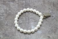 "White Pearl Note Bracelet The White Pearl Note Bracelet is made from faux glass pearls that are strung along an elastic cord. Also on the classic white bracelet is a Metal Bulldog Clip plated in Silver. The clip can be used to hold a notecard or a small piece of paper that can be tucked up in a long sleeve top for safekeeping. Each bracelet comes with a white 4-inch x 3-inch white drawstring, organza bag. The bracelet will fit a 6\" to 7 1/4\" wrist if you would like a custom size, please conta