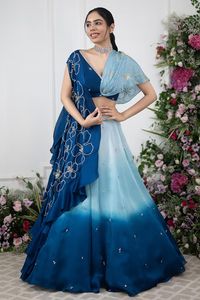 Blue ombre attached cancan lehenga with placement embroidery. Paired with a wrap style floral embroidered blouse and cape with floral embroidery. Components: 3 Pattern: Embroidery Type Of Work: Floral Neckline: V Neck Sleeve Type: Short Sleeves Fabric: Cape and Lehenga: Organza Satin, Blouse: Crepe Color: Blue Other Details:  Attached inner lining Lehenga: Length: 45 inches Attached cancan Blouse: Length: 14 Padded Note: All the jewellery worn by the model is not for sale Occasion: Sangeet - Aza