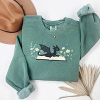 Dragon Book Sweatshirt, Fantasy Sweatshirt, Bookworm sweatshirt, bookish sweatshirt, book club sweatshirt, Book Lover, Book Crewneck Comfort Colors 1566 Sweatshirt  Luxurious comfort and style are what this unisex, garment-dyed sweatshirt is all about. It's made with 80% ring-spun cotton and 20% polyester and the fabric is 3-end garment-dyed, ring-spun, color-blast fleece with a 100% cotton face. Each sweatshirt comes with a relaxed fit, a rolled-forward shoulder, and a back neck patch.  .: 80% ring-spun cotton, 20% polyester .: Medium-heavy fabric (9.5 oz /yd² (322.1 g/m .: Relaxed fit .: Sewn in twill label .: OEKO-TEX certified low-impact dyes