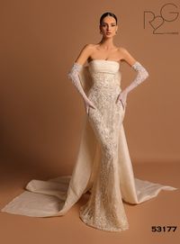 Experience refined elegance with Tarik Ediz 53177! This mesmerizing dress has a fitted bodice with ruched details and intricate beaded embellishments. The empire waistline creates a graceful silhouette, while a delightful bow at the back adds allure. The ethereal overskirt and captivating train guarantee a memorable, elegant look.