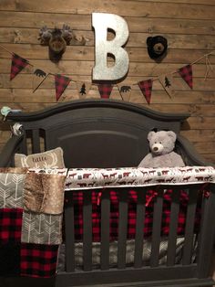 a baby crib with a teddy bear in it and the letter b on the wall