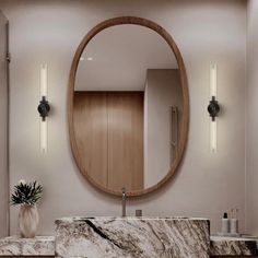 a bathroom with marble counter top and round mirror