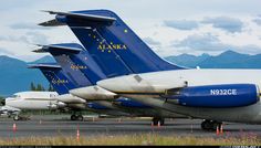 several airplanes are lined up on the tarmac at an airport with mountains in the background