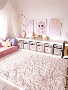 a room with white carpet, pink couch and storage bins