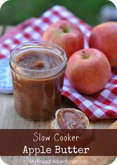 a jar of apple butter sitting on top of a wooden table next to some apples