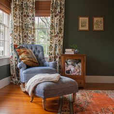 a blue chair sitting in front of a window next to a wooden dresser and baby crib