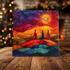 a painting on a wooden table with a christmas tree in the background