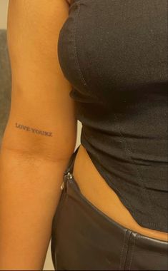 a woman's arm with the word love yourself tattooed on her left side, in black ink