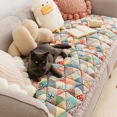 a black cat laying on top of a couch next to stuffed animals