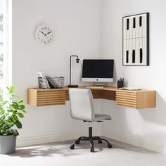 a corner desk with a computer on it and a plant in front of the window