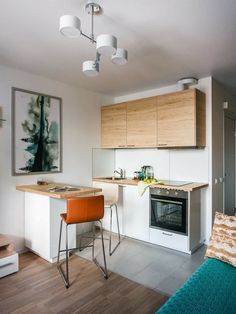 a kitchen with an oven, sink and stools next to a living room area