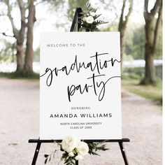 a welcome sign for a graduation party with flowers on it and greenery in the background