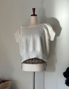 a mannequin with a white sweater on it's head and an object in the background