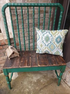 a green bench with a pillow on top of it next to a brick wall and door