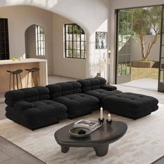 a large black sectional sofa sitting on top of a rug in a living room next to a table