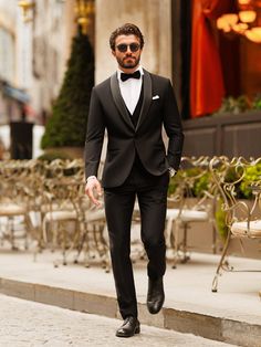 a man in a tuxedo is walking down the street