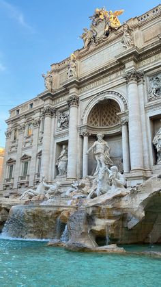 an ornate building with statues and fountains in front of it