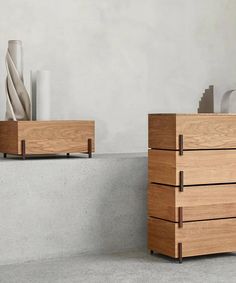 two wooden drawers sitting next to each other on top of a cement floor in front of a white wall