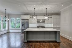 a large kitchen with an island in the middle and two lights hanging from the ceiling