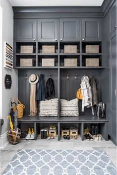 an organized mud room with gray cabinets and baskets on the shelves, white rugs and blue carpet