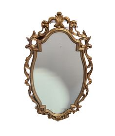 an ornate gold framed mirror against a white wall