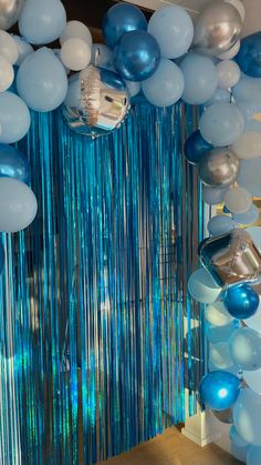 blue and white balloons are hanging from the ceiling