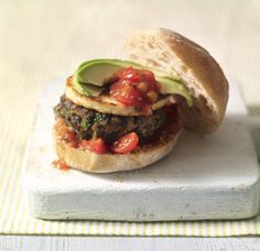 a burger with tomatoes, avocado and other toppings