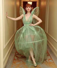 a woman in a green dress walking down a hallway