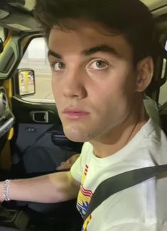 a man sitting in the driver's seat of a car looking at the camera