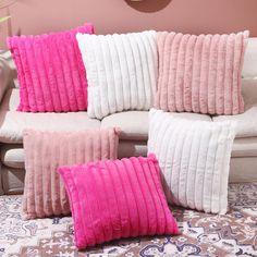 pink and white pillows sitting on top of a couch in front of a wall mounted clock