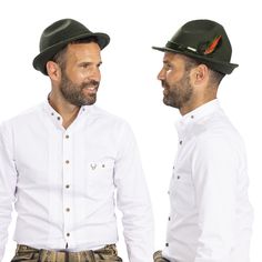 two men in white shirts and green hats are facing each other with their hands on their hips