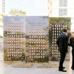 a man and woman standing in front of two large posters that have flowers on them