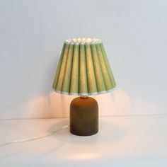 a green lamp sitting on top of a table next to a white wall and floor