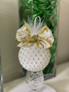 a glass ornament with a bow on it sitting on a table next to a vase