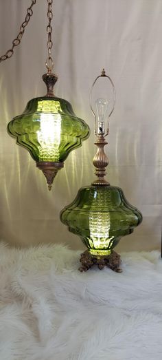 two green glass lamps sitting on top of a white fur covered floor