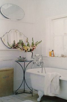 a white bath tub sitting next to a sink under three round mirrors on the wall