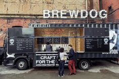 two people standing in front of a food truck with the word brewdog written on it