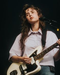 a man with long hair playing an electric guitar