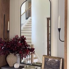 a mirror sitting on top of a dresser next to a vase with flowers in it