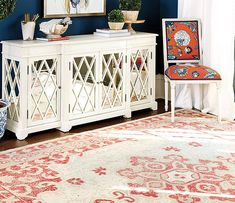 a living room with blue walls and red rugs on the floor next to a white cabinet