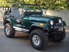 a green jeep parked in front of a fence