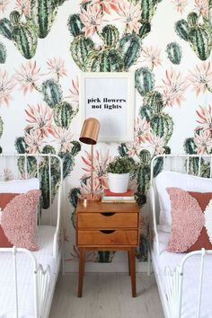 two twin beds in front of a cactus wallpaper with pink and green leaves on it