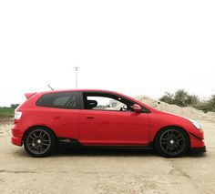 a red car is parked in the dirt