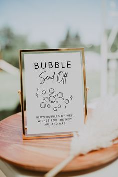 a sign that is on top of a wooden table next to a white feather ornament