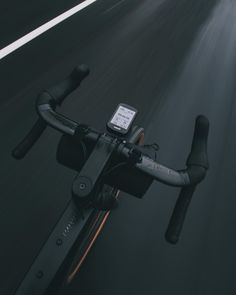 a bike is riding down the road with its handlebars extended and an electronic device on it