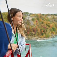 a woman smiles as she looks out over the water